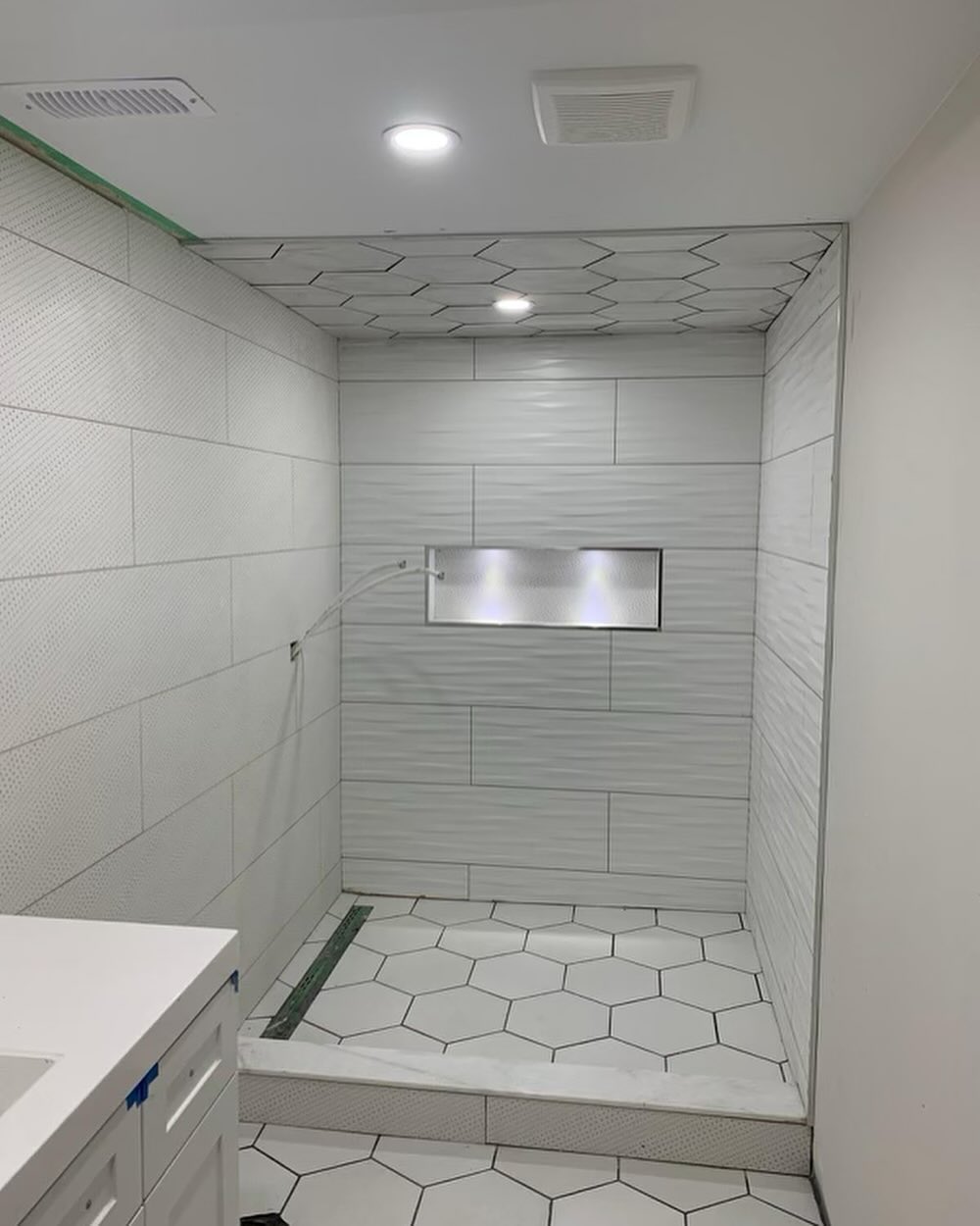 New walk-in shower with geometric floor and tiled walls